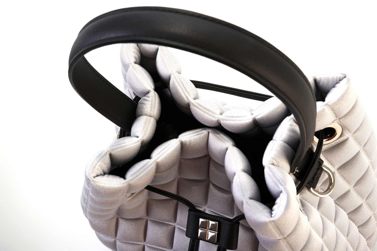 un dettaglio sull'apertura della borsa a mano da donna modello secchiello della collezione BPrime Bags, in tessuto termoformato 3D Cube, con chiusura con lacci, manico e tracolla rimovibile in pelle.